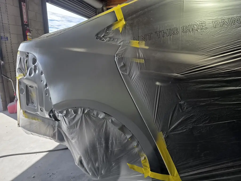 Rear quarter panel in primer with the rest of the car masked off